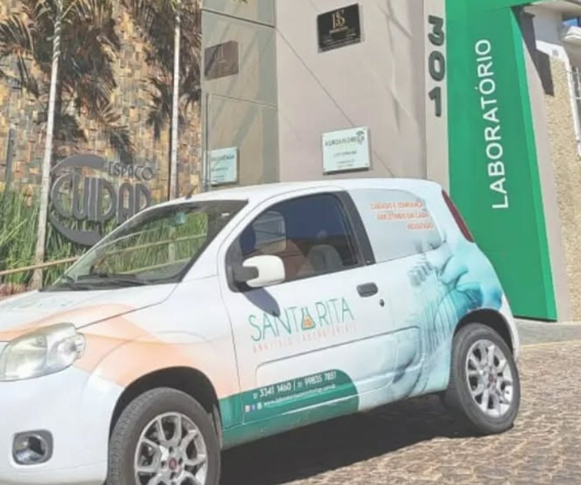 Fachada da matriz do Laboratório Santa Rita em Itapecerica, com o totem da marca e o carro do laboratório